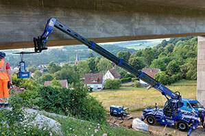 Teleskoplader TSR 3060 mit ausgefahrenem Teleskoparm bei Einsatz an Brücke