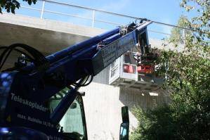 Telelader mit Arbeitskorb an Brücke im Einsatz