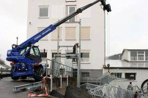 Abgestützter Teleskoplader mit Seilwinde beim Transport von Treppengeländer